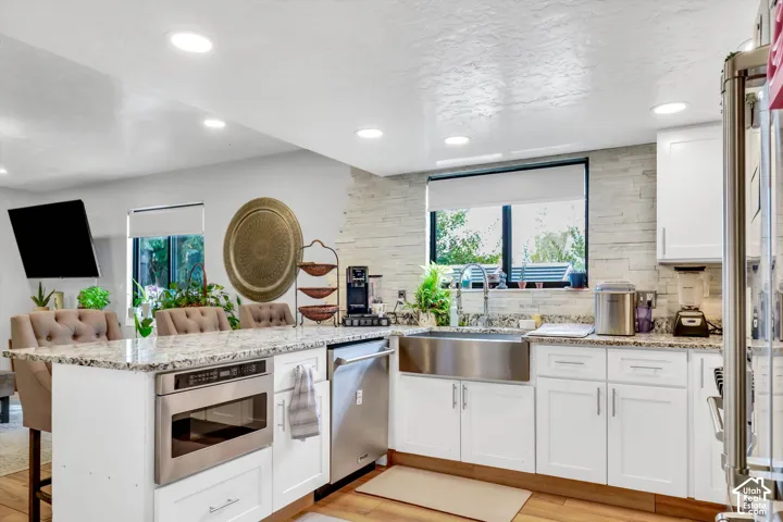 Kitchen featuring Thor stainless steel appliances, granite countertops, bar dining and a full tile backsplash