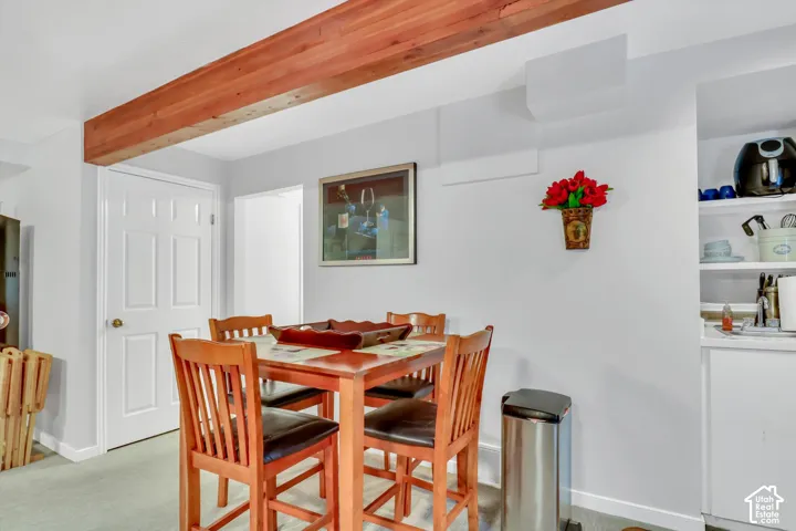 Exposed wood beam ceiling, white paneled interior door, built-in open shelving, compact sink area