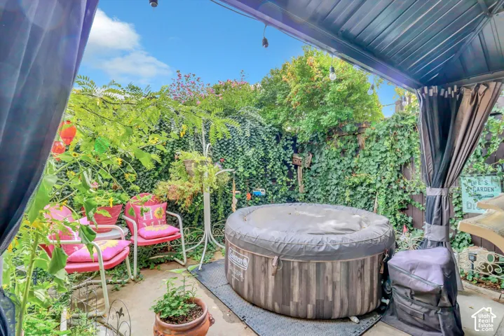 Covered outdoor patio with string lighting, an inflatable spa, and privacy curtains