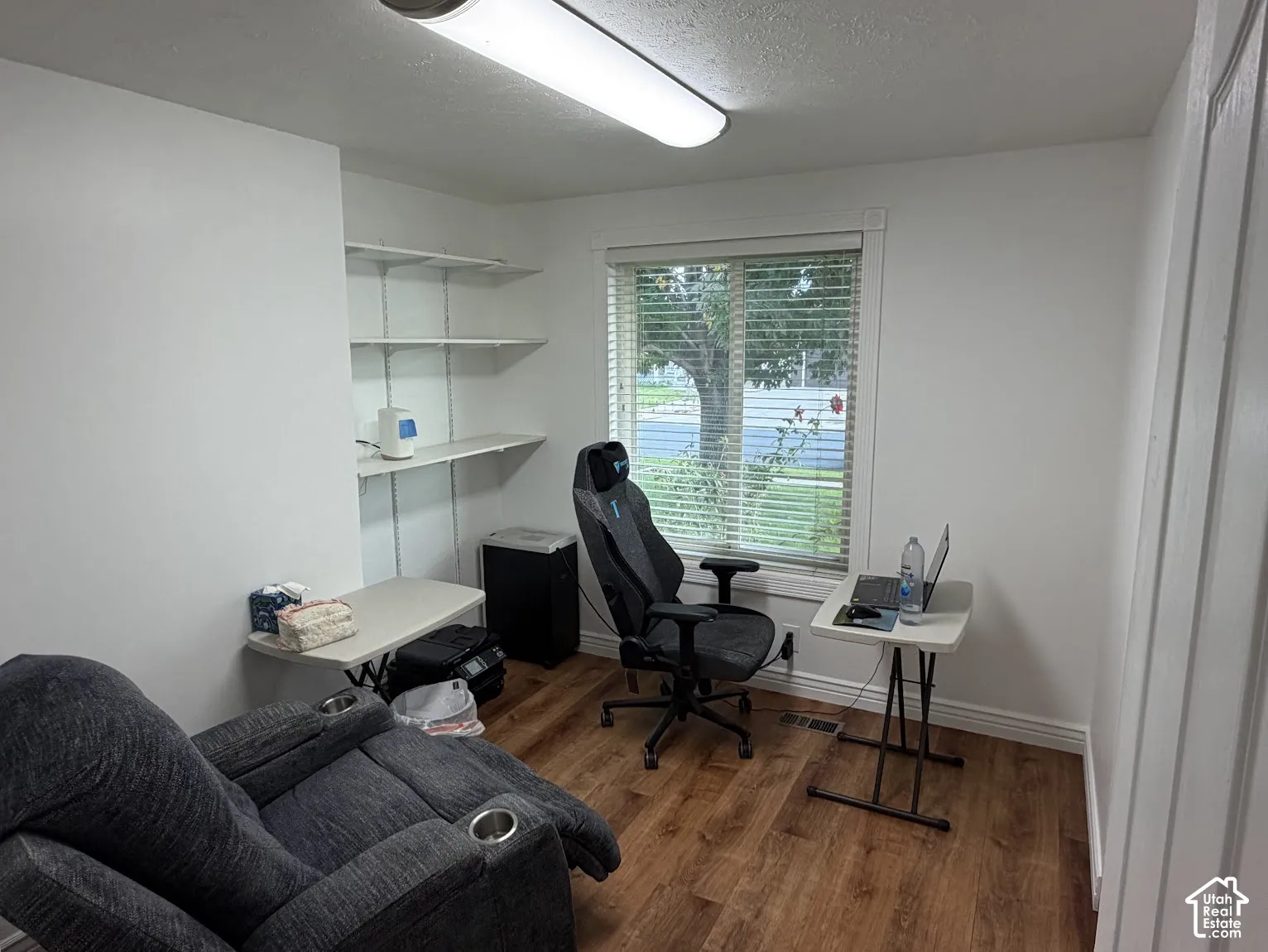 Wood-finish flooring, built-in wall shelving, and a prominent window