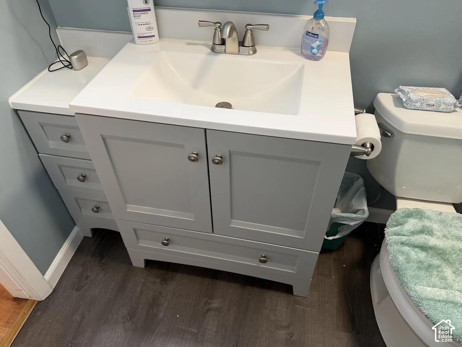 Bathroom vanity with a white countertop, integrated rectangular sink, brushed nickel faucet, and gray shaker-style cabinetry with drawers