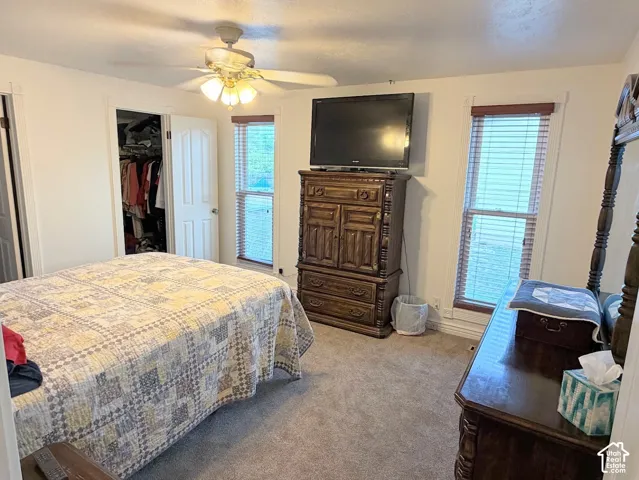 Carpeted room featuring a ceiling fan, two windows with blinds, and a built-in closet with an interior light