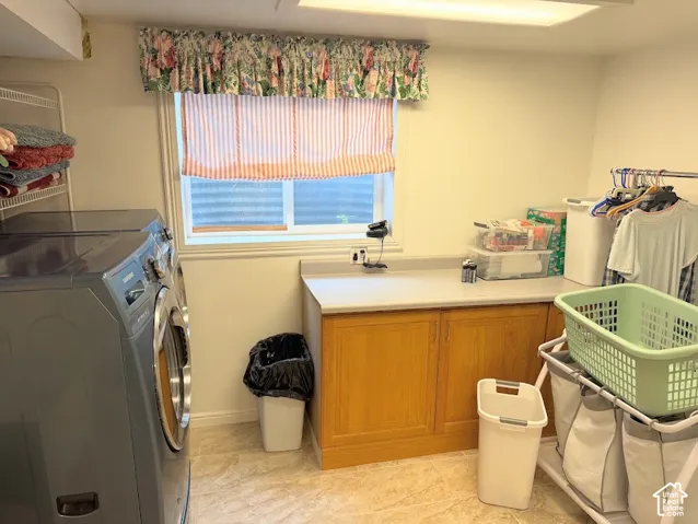 Dedicated laundry room featuring wood-finish cabinetry, a neutral countertop, and a window for natural illumination