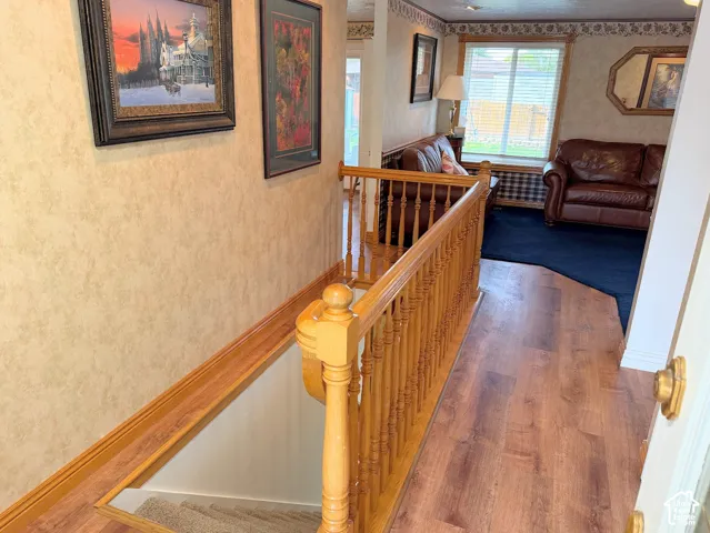 Wood-finish flooring, staircase with natural wood railing, and textured wall finish