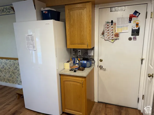 Wood-finish flooring with a white residential-style door and a built-in wood-finish cabinet