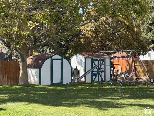 Expansive backyard featuring a mature tree, two storage sheds with gambrel roofs, and a wooden privacy fence