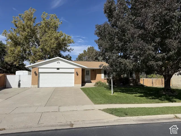 Brick facade, white garage door, concrete driveway, front lawn, mature trees