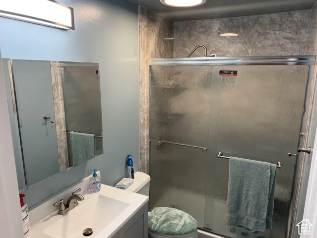 Bathroom with a shower enclosure featuring a sliding glass door, a vanity with an integrated sink, and an overhead light fixture