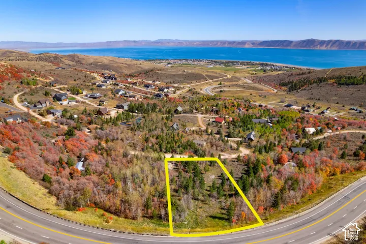 Expansive land parcel with direct road frontage, surrounded by mature trees, and featuring prominent water and mountain scenery