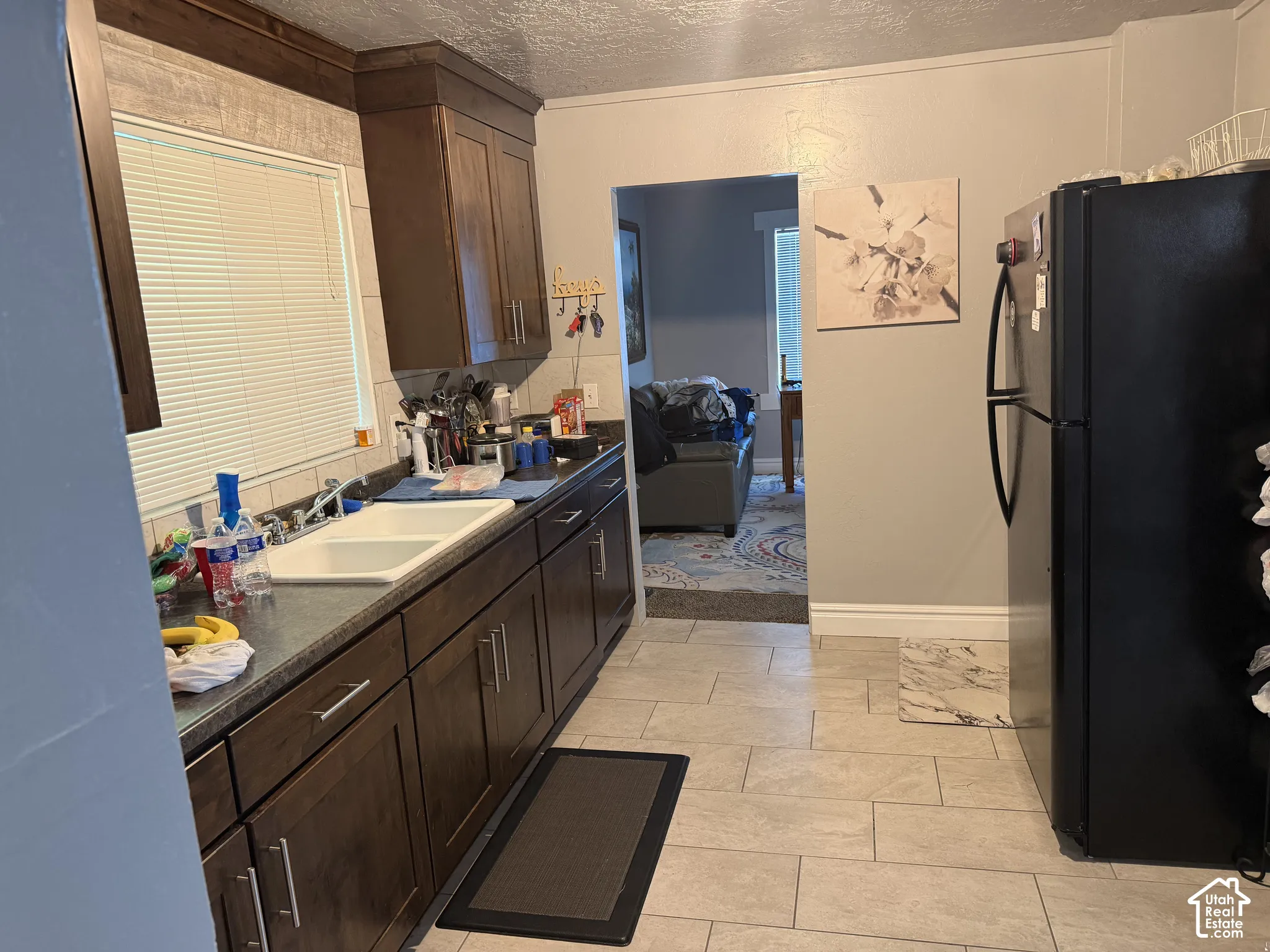 Wood-finish cabinetry with silver-tone hardware, a double basin sink, and tile flooring