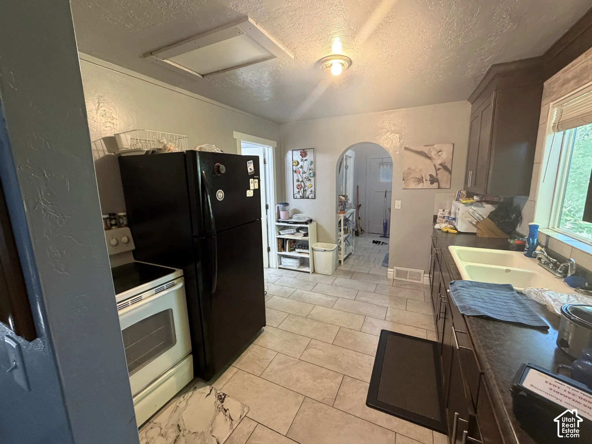 Kitchen featuring tile flooring, built-in cabinetry, a double basin sink, and an arched doorway