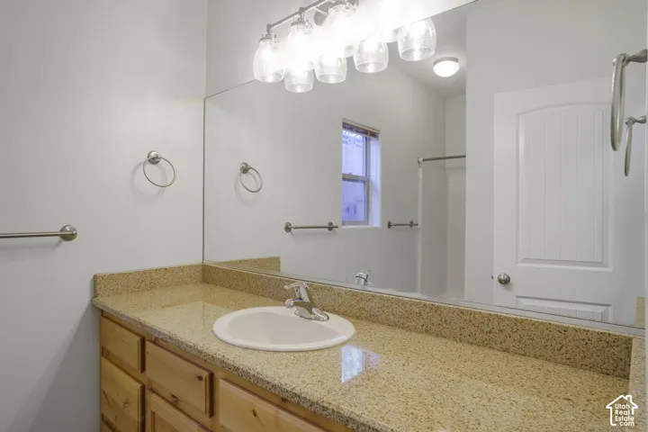 Vanity with a light-toned solid surface countertop, an undermount sink, and a chrome-finish faucet