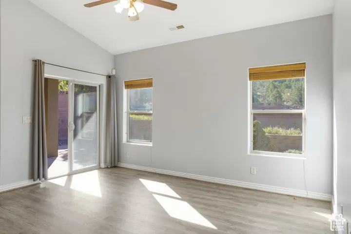 Vaulted ceiling with a ceiling fan, wood-finish flooring, and sliding glass door access to an outdoor patio