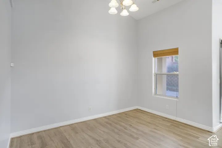 Wood-finish flooring with white baseboards, a light fixture, and a window with blinds