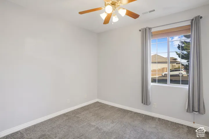 Wall-to-wall carpet flooring, a multi-pane window, and a ceiling fan with integrated lighting
