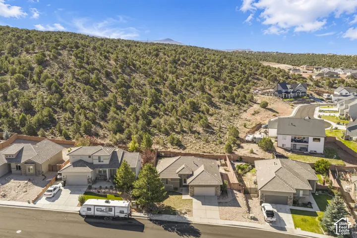 Residential neighborhood with diverse home styles, paved streets, and a natural, undeveloped hillside backdrop