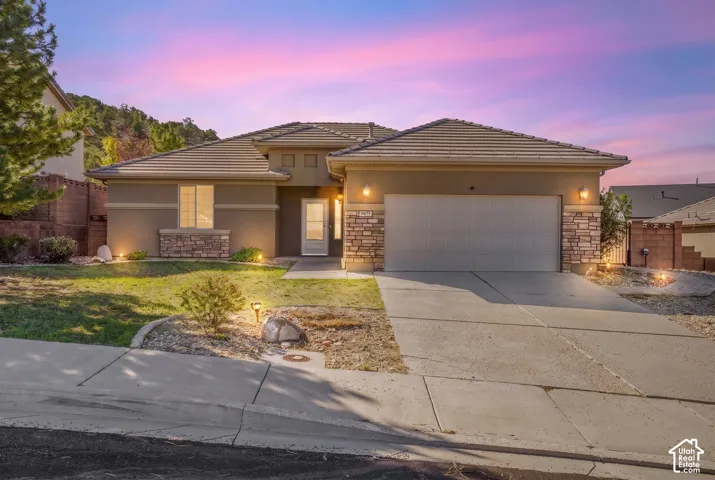 Stucco exterior with stone accents, a tile roof, an attached two-car garage, and a concrete driveway