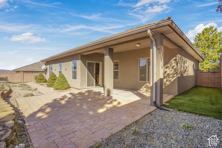 Expansive patio with stamped concrete pavers, covered patio area, and sliding glass door access