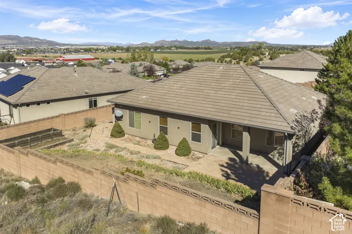 Tile roof, stucco exterior, covered patio, fenced yard, and mountain backdrop