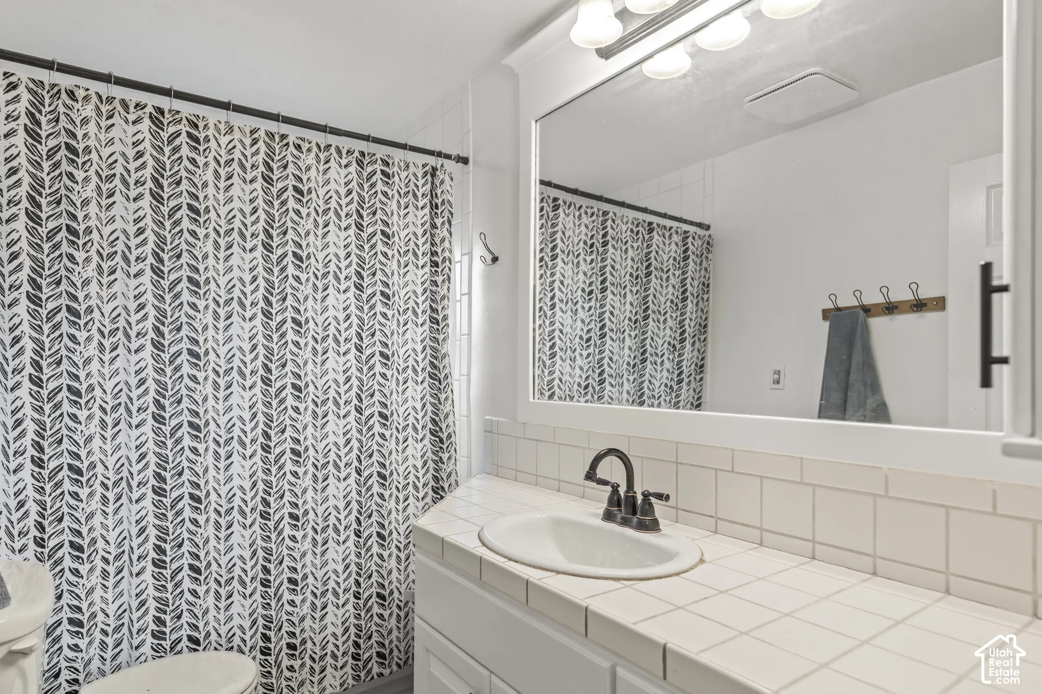 White tiled vanity with an integrated sink and dark-finish faucet