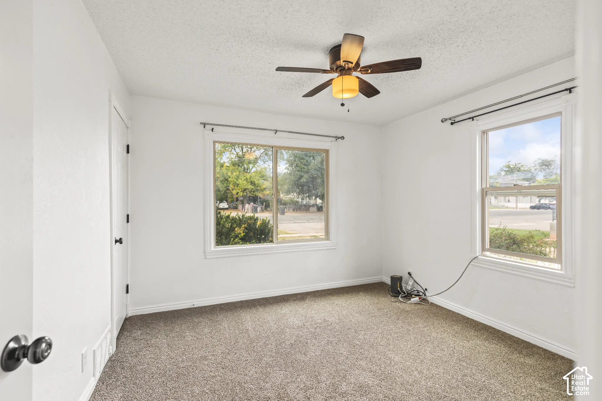 White walls, textured ceiling, and a brown carpeted floor