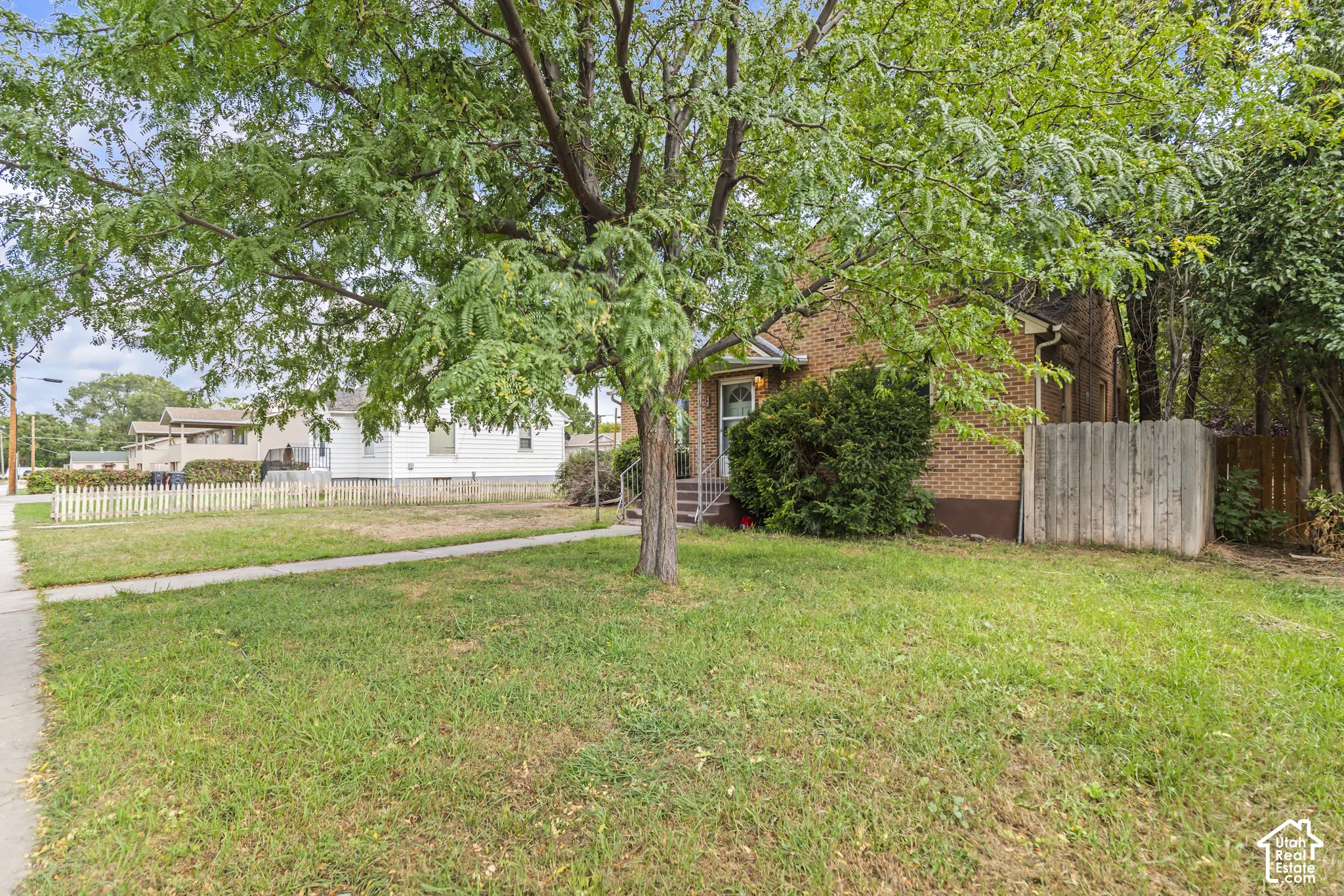 Brick exterior with a mature tree, front porch, and established shrubbery