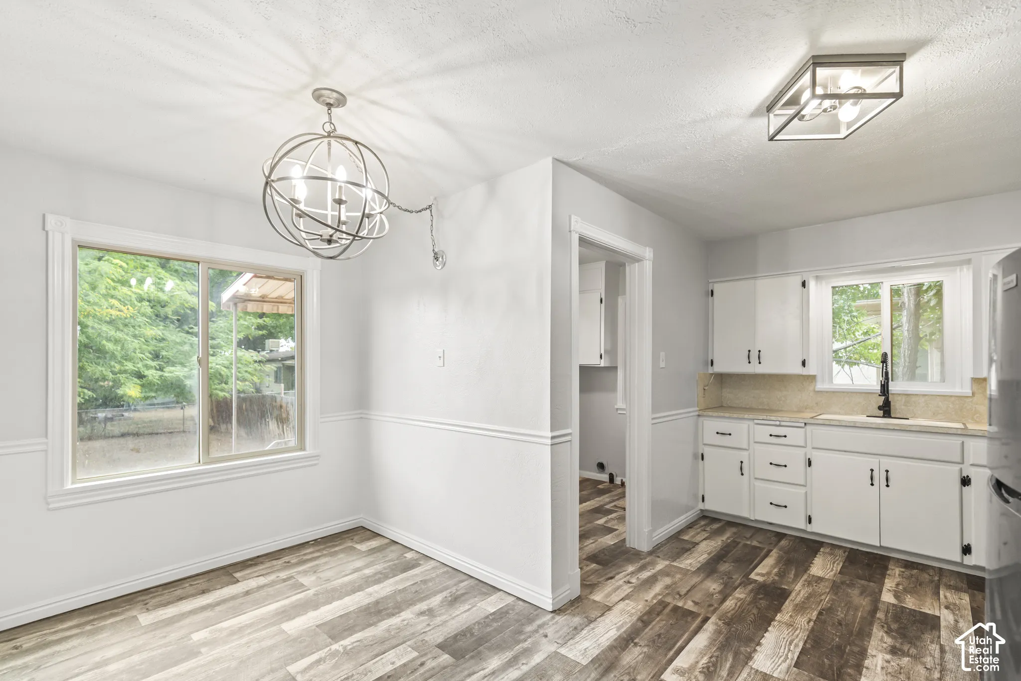 Wood-finish flooring, white wall paneling, and an orb chandelier