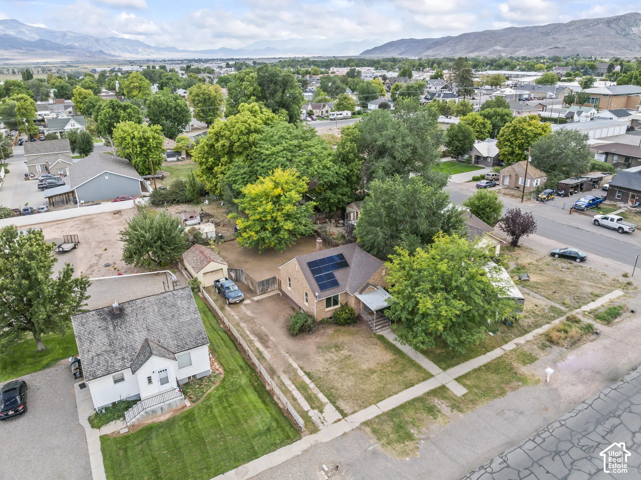 Aerial view showcasing a corner lot with mature landscaping, including established trees and manicured lawn