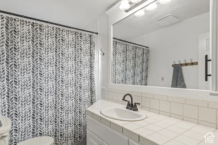 White tiled vanity with an integrated sink and dark-finish faucet