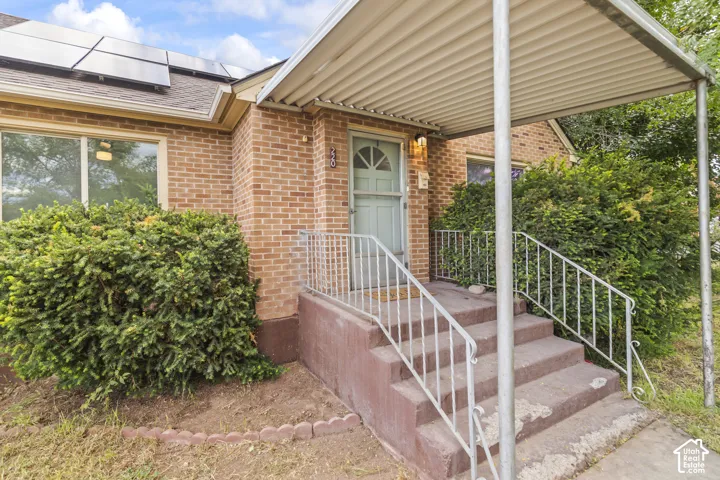 Brick exterior with a covered front porch featuring metal railings and concrete steps