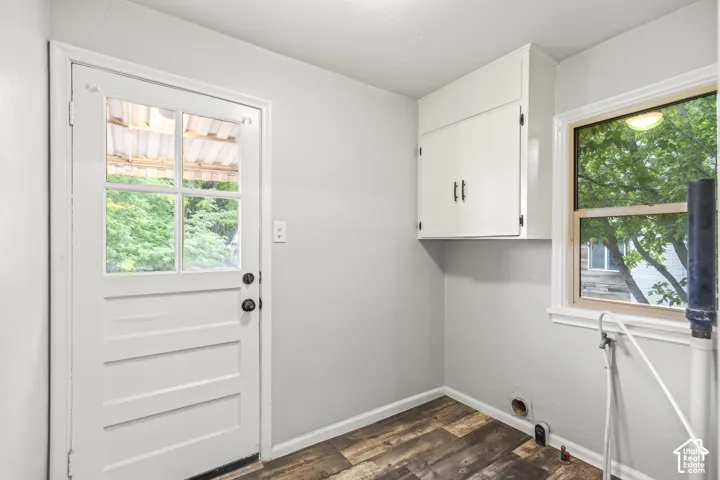 Bright mudroom featuring white shaker-style cabinetry with dual handles, wood-finish flooring, and abundant natural light from dual windows