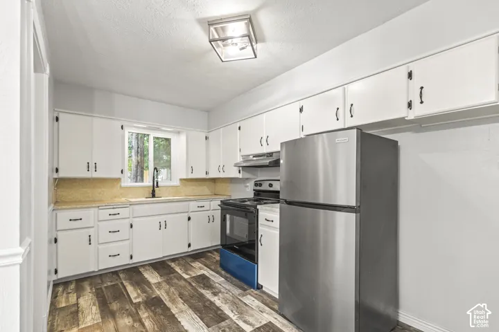 Kitchen featuring white cabinetry, wood-finish flooring, stainless steel appliances, and a window above the sink