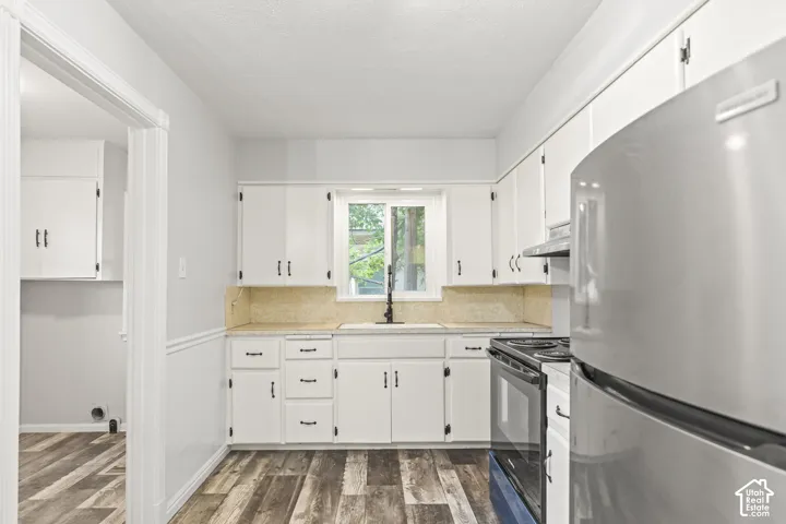 Bright kitchen featuring white cabinetry with hardware accents, stainless steel appliances including a gas range, light wood-finish countertops, and wood-finish flooring with a linear plank pattern