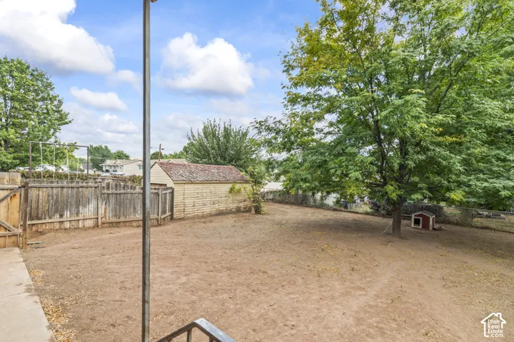 Spacious dirt arena with sturdy wood-finish fencing, mature shade trees throughout the grounds, and outbuilding structures