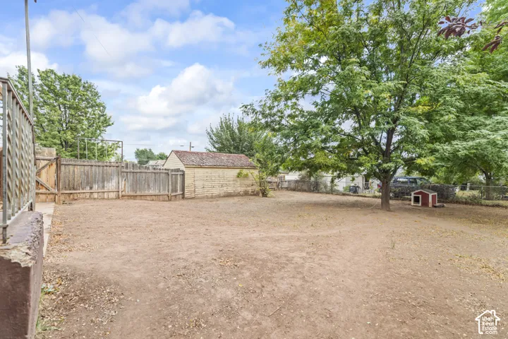 Expansive yard space featuring mature trees, wood fencing, and a detached storage shed