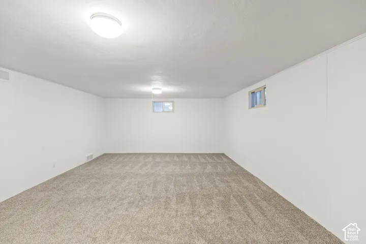 Spacious room featuring neutral carpet, white walls, and two ceiling-mounted light fixtures