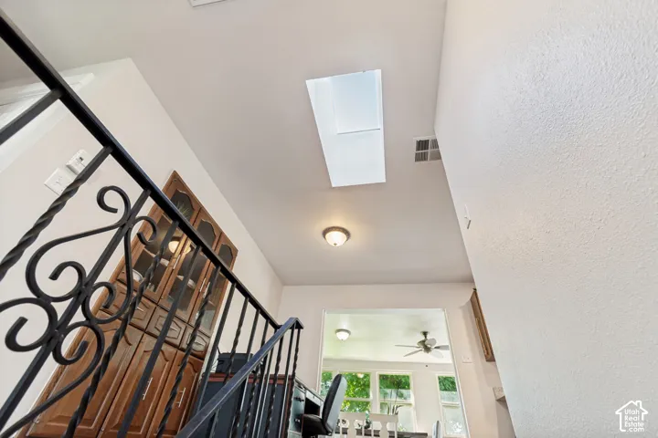 Ornate wrought iron railing, overhead skylight, recessed ceiling light, wood-finish built-in cabinetry, and ceiling fan