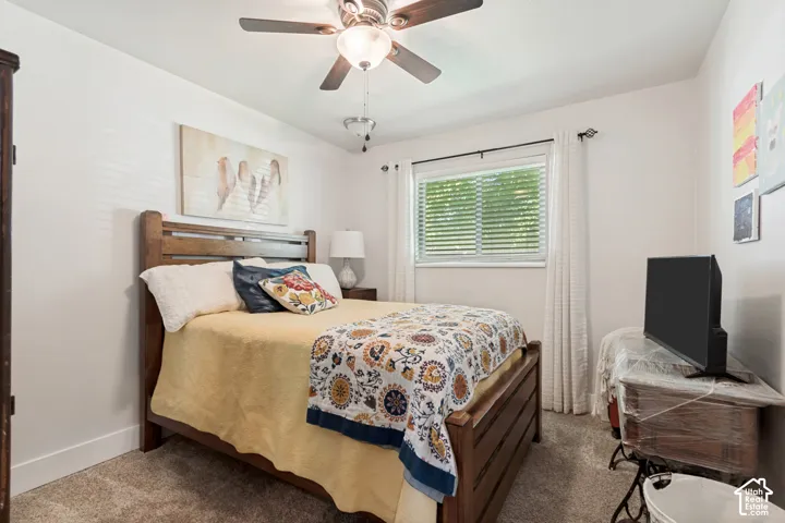 Recessed window with blinds, ceiling fan with light fixture, light-toned wall paint, and textured carpet flooring