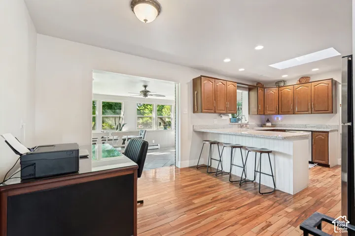 Wood-finish flooring, recessed lighting, skylight, kitchen island with seating, and wood cabinetry