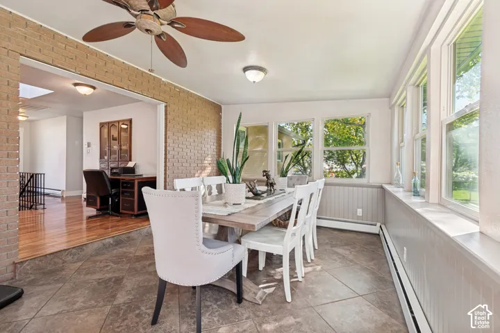 Tiled flooring, exposed brick accent wall, wood-finish ceiling fan, multiple windows with paneling, and a stepped entry