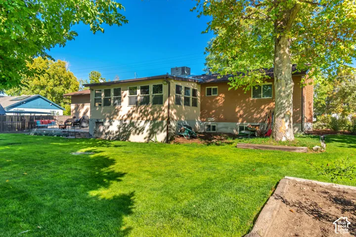 Expansive green lawn with mature trees, a concrete patio area, and a raised garden bed