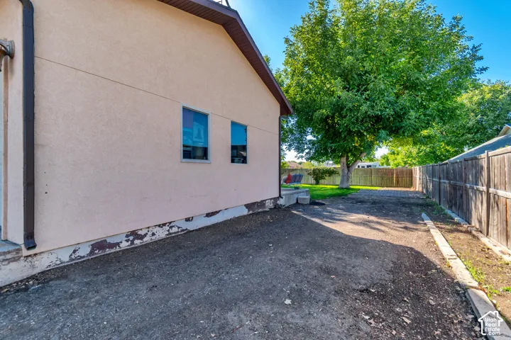 Exterior stucco siding with two windows and a brown gutter system