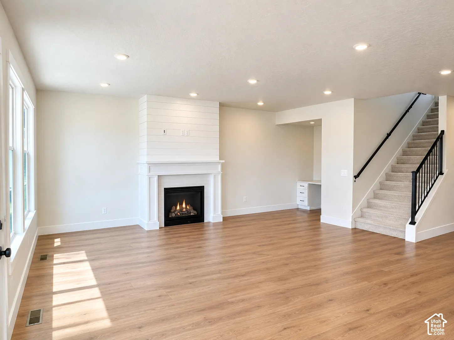 Wood-finish flooring, recessed lighting, and a built-in fireplace with shiplap detailing