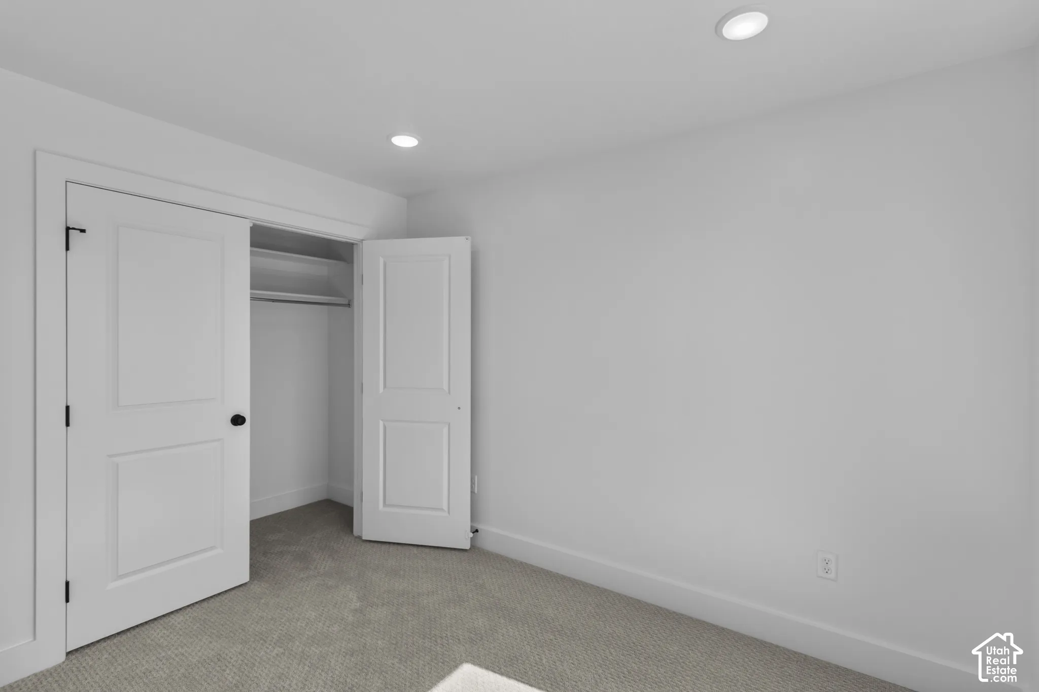 Recessed ceiling lighting, white painted walls, and neutral carpet flooring