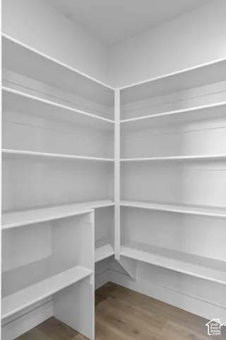 Expansive walk-in pantry with white shelving and wood-finish flooring