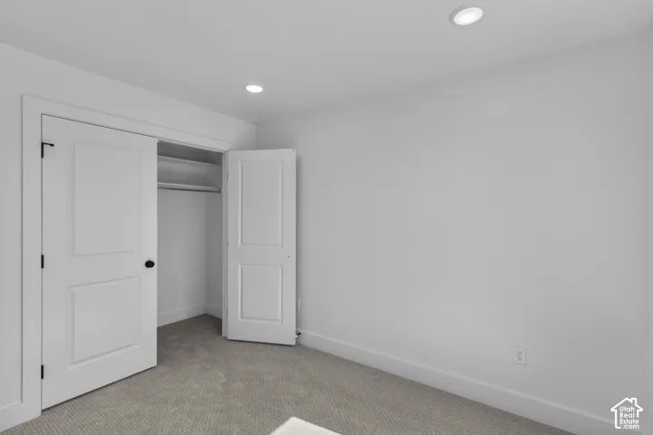 Recessed ceiling lighting, white painted walls, and neutral carpet flooring