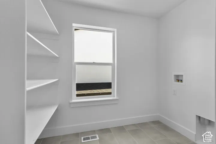 Built-in shelving, white window with trim, tile flooring, and dedicated appliance hookups