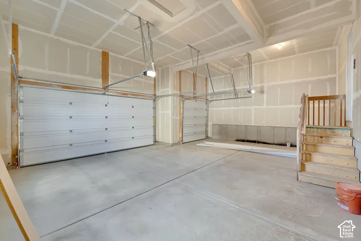 Concrete flooring, exposed ceiling joists, two garage doors, and unfinished walls