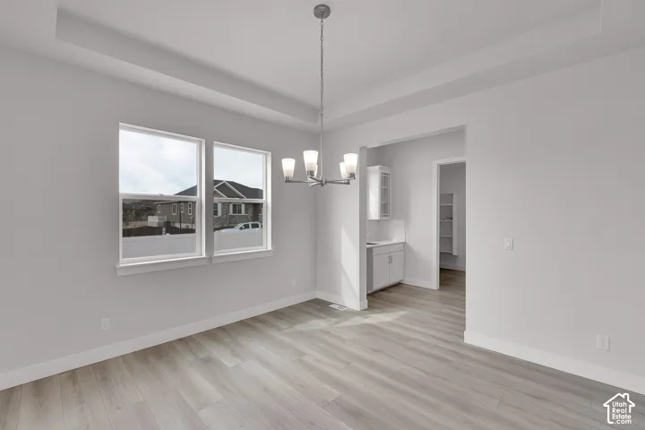 Recessed ceiling, tray ceiling, wood-finish flooring, contemporary chandelier, built-in cabinetry with solid surface countertop
