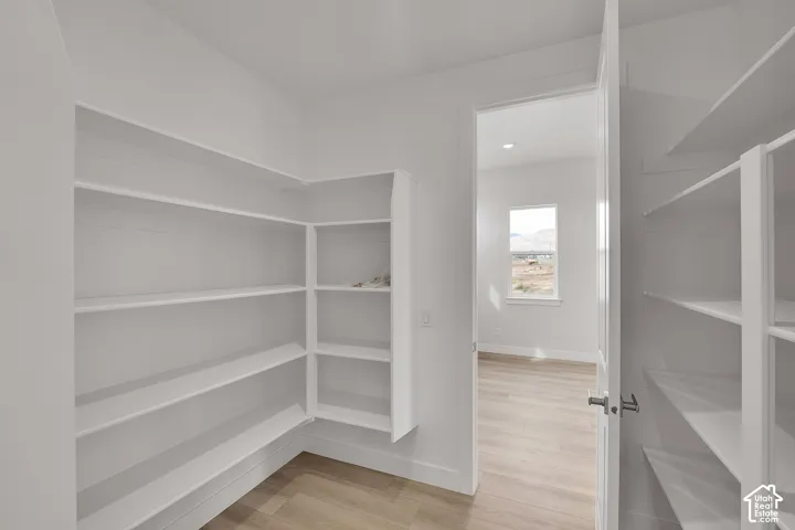 Built-in shelving, wood-finish flooring, recessed lighting, and white walls